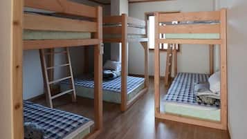 Una habitación con tres literas, cada una con una escalera, y un escritorio pequeño en el centro.