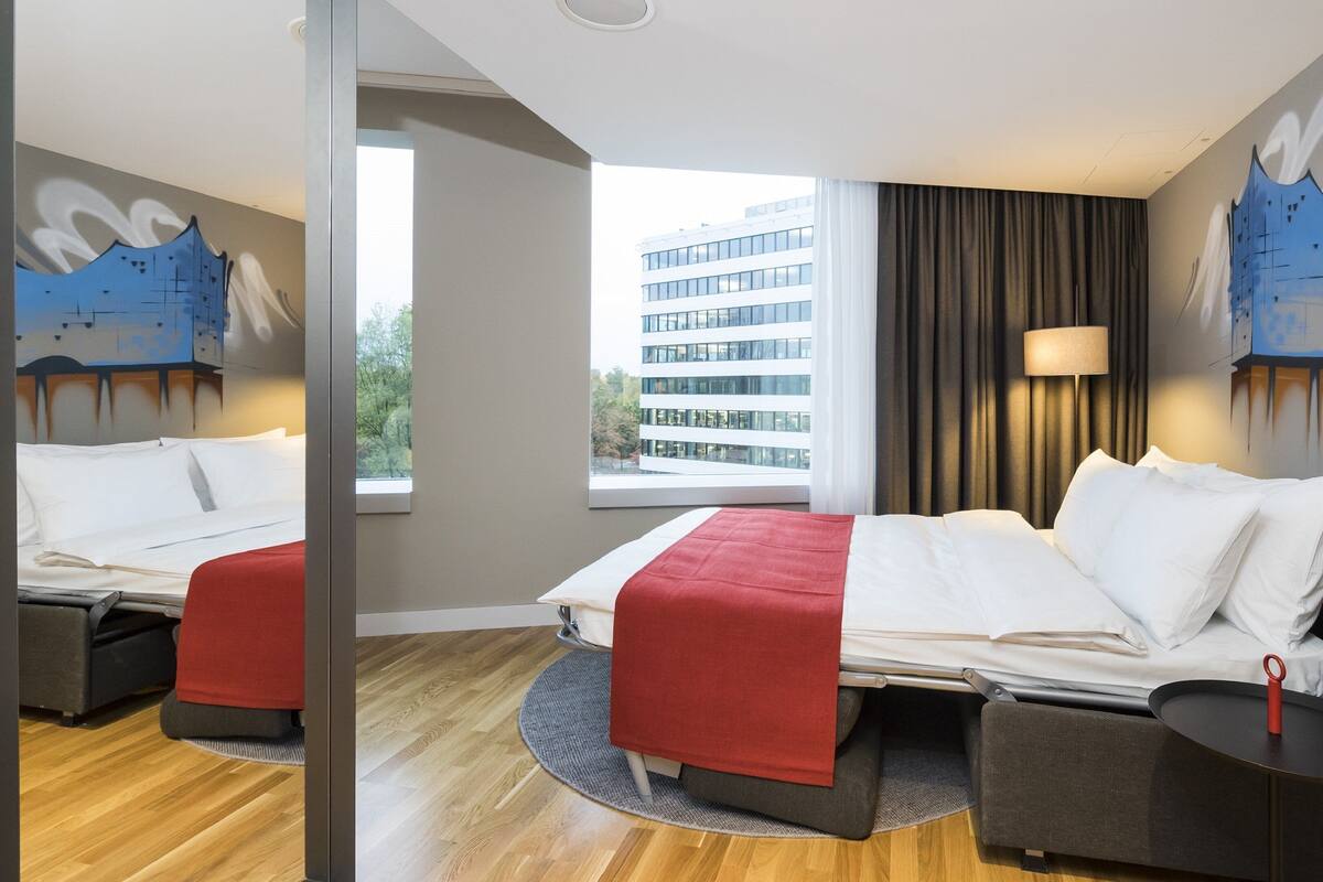 Une chambre d’hôtel avec un lit, un canapé, une petite table et un miroir.