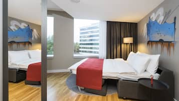 A hotel room with a bed, a sofa, a small table, and a mirror.