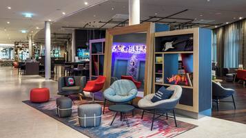 Un moderno espacio lounge con asientos, barra y pantalla digital.