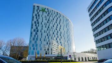 A modern hotel building with a curved facade, large windows, and a Holiday Inn sign.