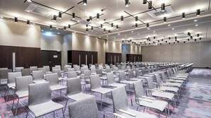 Ein Konferenzraum mit grauen Stühlen, einem gemusterten Teppich und einer Decke mit mehreren Leuchten.