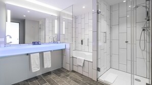 Ein modernes Badezimmer mit einem großen Waschbecken, einem Spiegel und einer Dusche mit Glastrennwand.