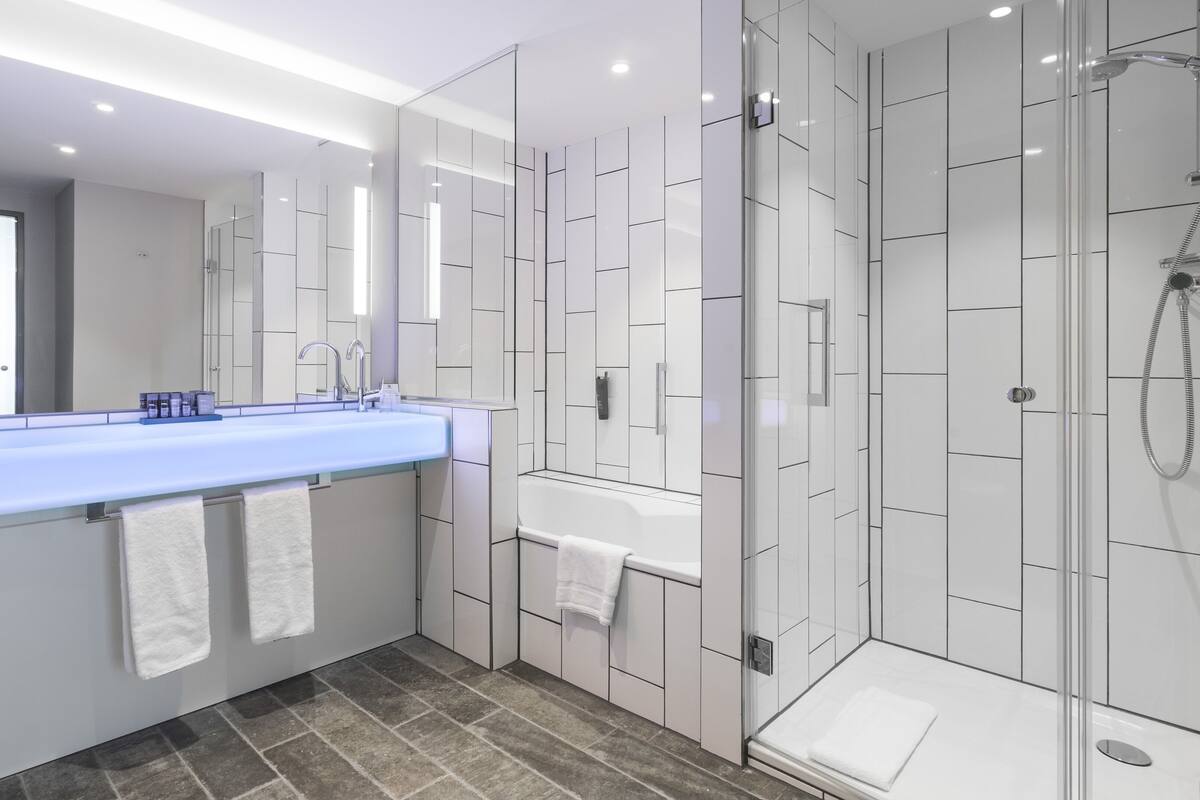Une salle de bain moderne avec un grand lavabo, un miroir et une douche en verre.