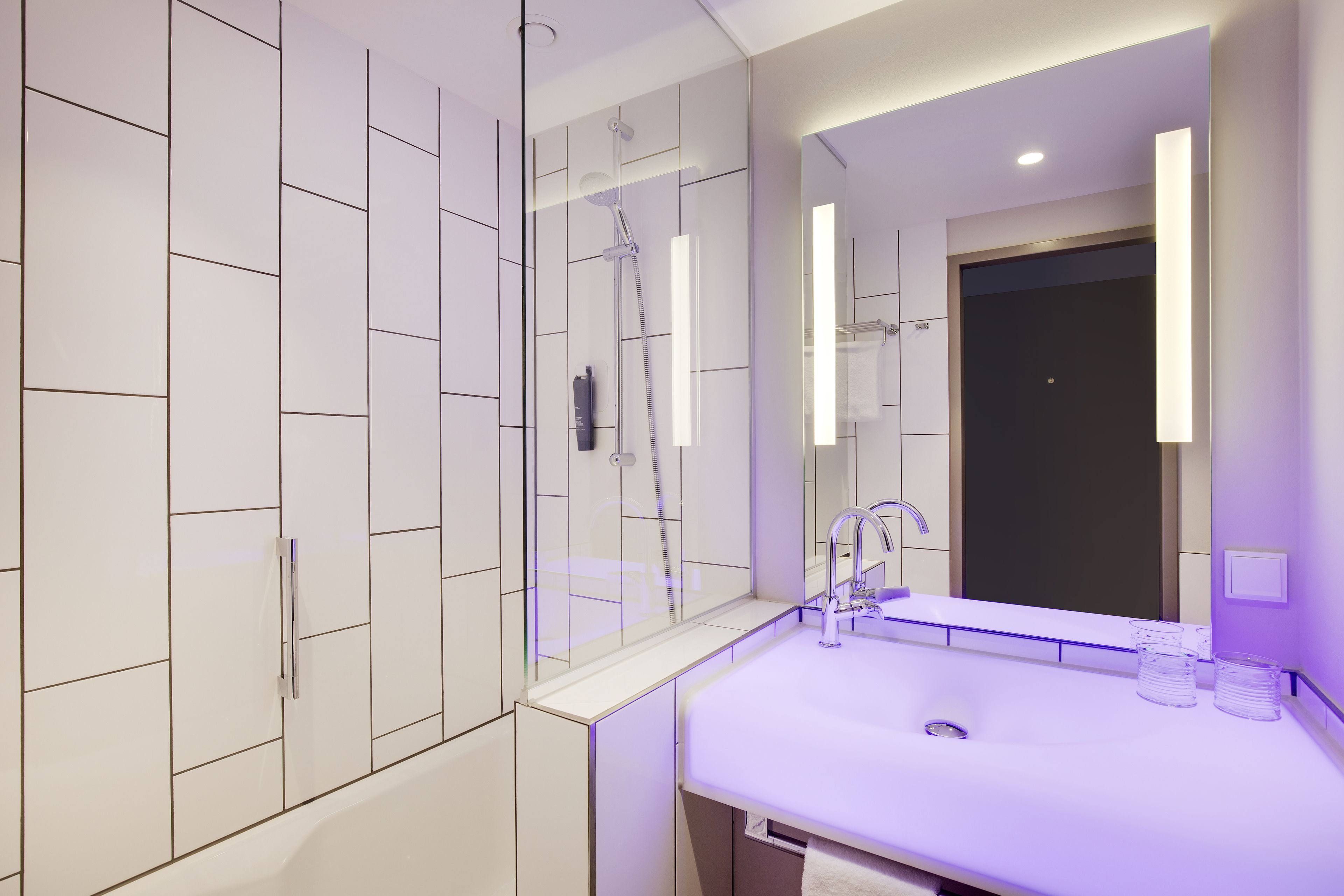 A modern bathroom with a large mirror, a sink, and a shower.