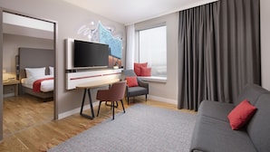 Ein modernes Hotelzimmer mit Flachbildfernseher, einer Couch, einem Sessel, einem Schreibtisch und einem Bett.