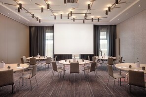 Een vergaderzaal met een groot scherm, meerdere tafels en stoelen voor vergaderingen.