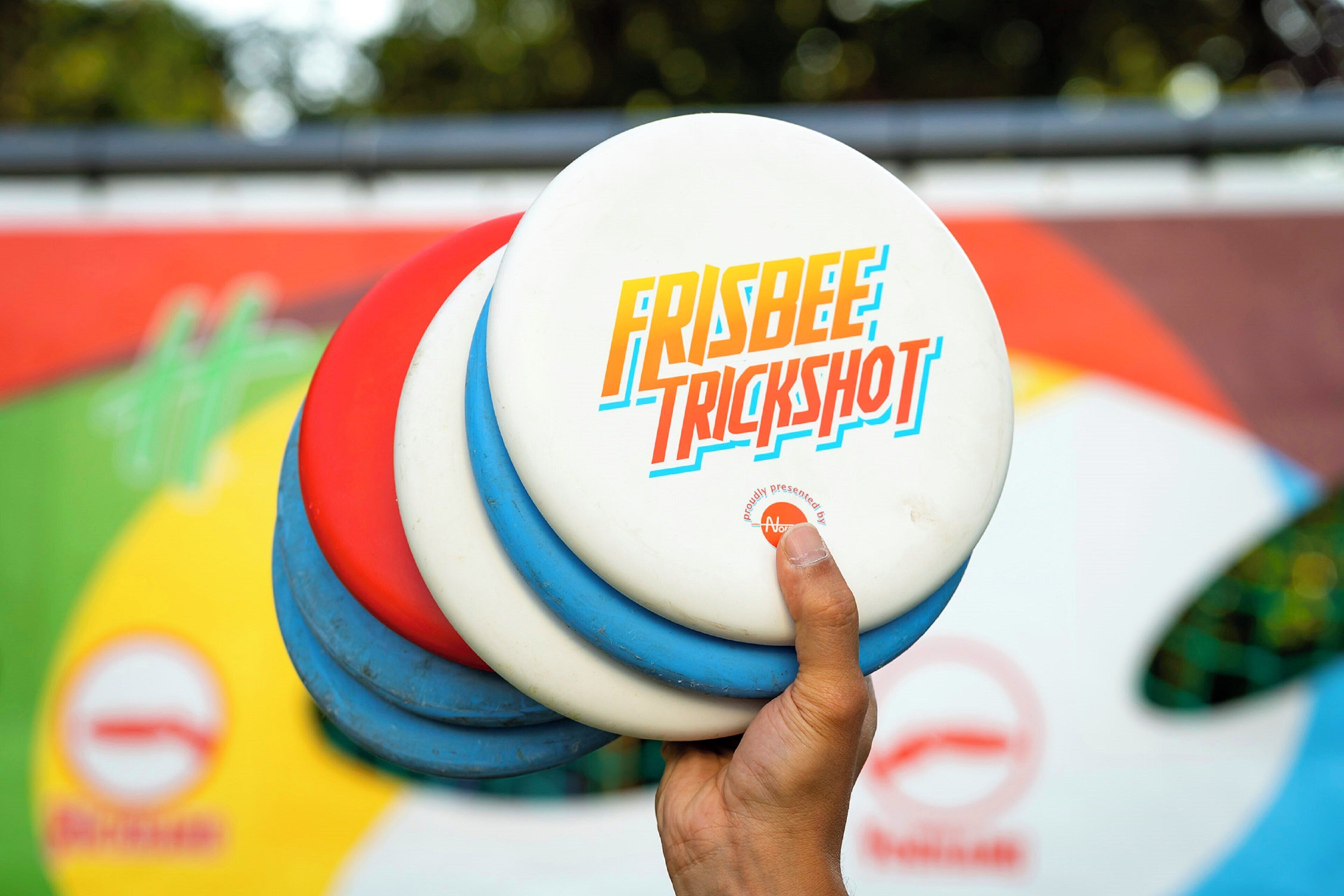 Een hand die een frisbee vasthoudt, met de tekst 'FRISBEE TRICKSHOT' erop.
