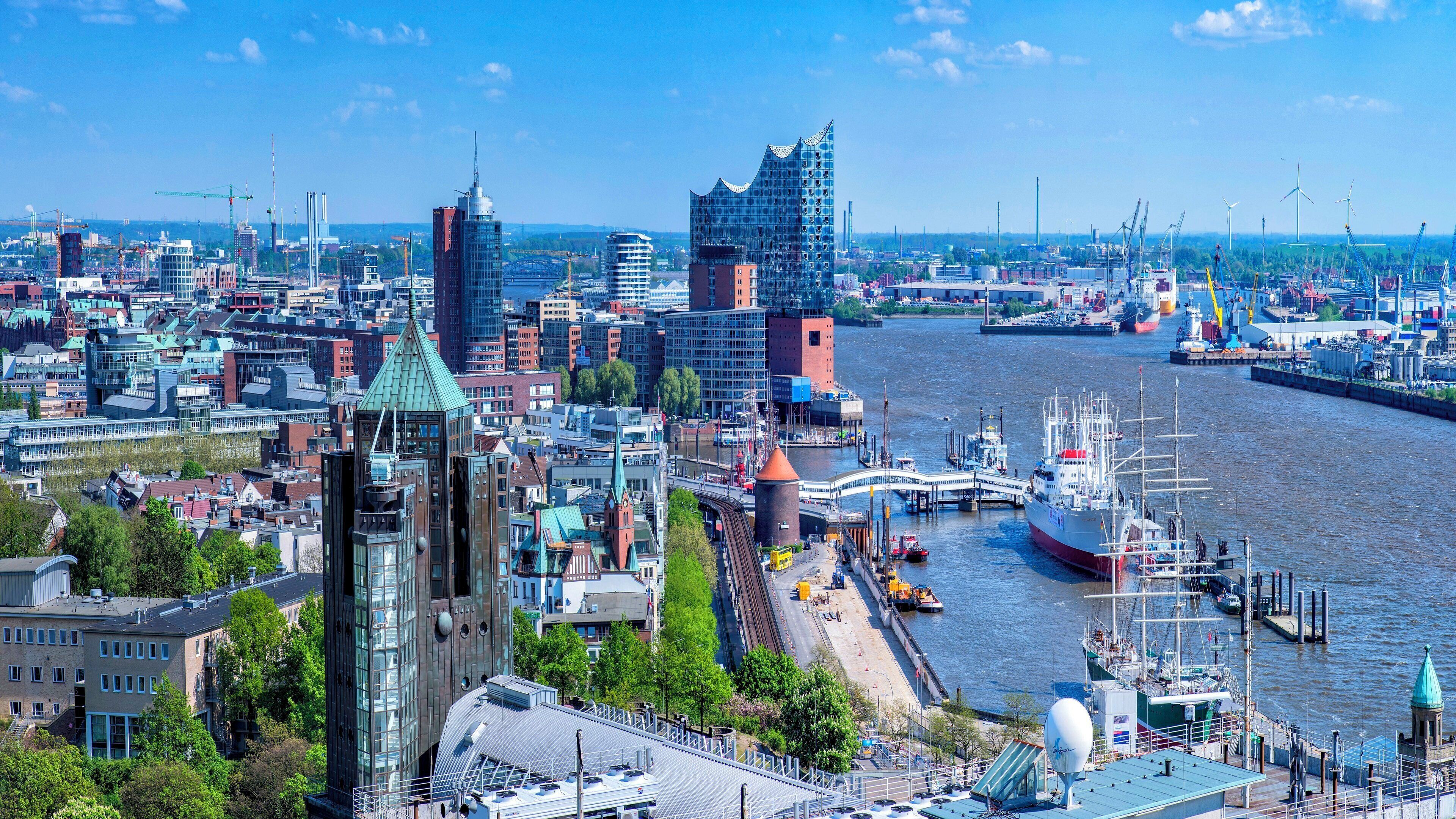 A cityscape with a river, modern buildings, and a large ship docked at the port.