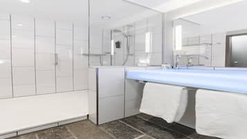 Une salle de bain moderne avec un grand miroir, des carreaux blancs, un lavabo bleu et un espace douche.