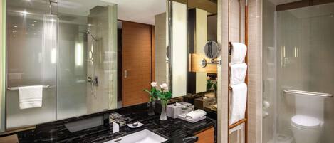 A modern bathroom with a black marble sink, a large mirror, a glass shower enclosure, and a wooden vanity.