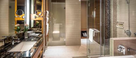 A modern bathroom with a large mirror, a bathtub, a glass-enclosed shower, and a vanity with a marble countertop.