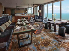 A modern dining area with a view of the ocean, featuring a mix of seating options including a sofa, chairs, and a dining table.