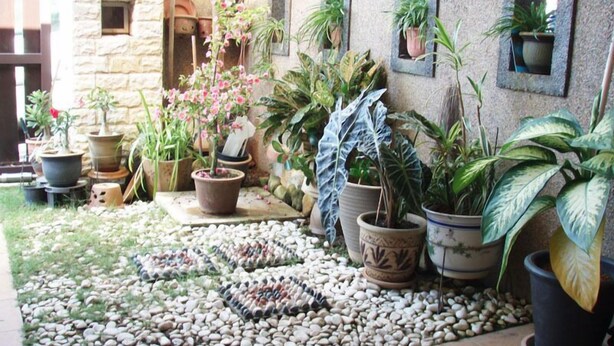 A courtyard with potted plants, pebbles, and a stone building. - Garden Vacation Suite (Bentong)