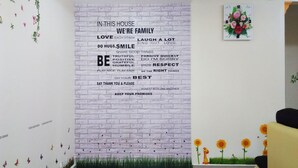 A room with a white brick wall and a motivational quote. There is a clock on the wall and a small plant on the right. - Garden Vacation Suite (Bentong)