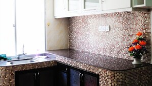 A kitchen with a tiled backsplash, a sink, cabinets, and a window. - Garden Vacation Suite (Bentong)