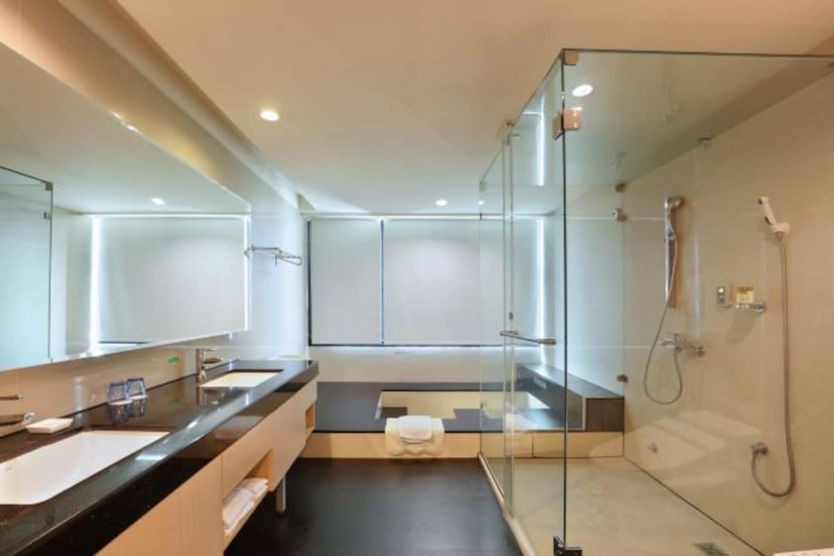 A modern bathroom with a glass shower enclosure, a large mirror, and a dual sink vanity.