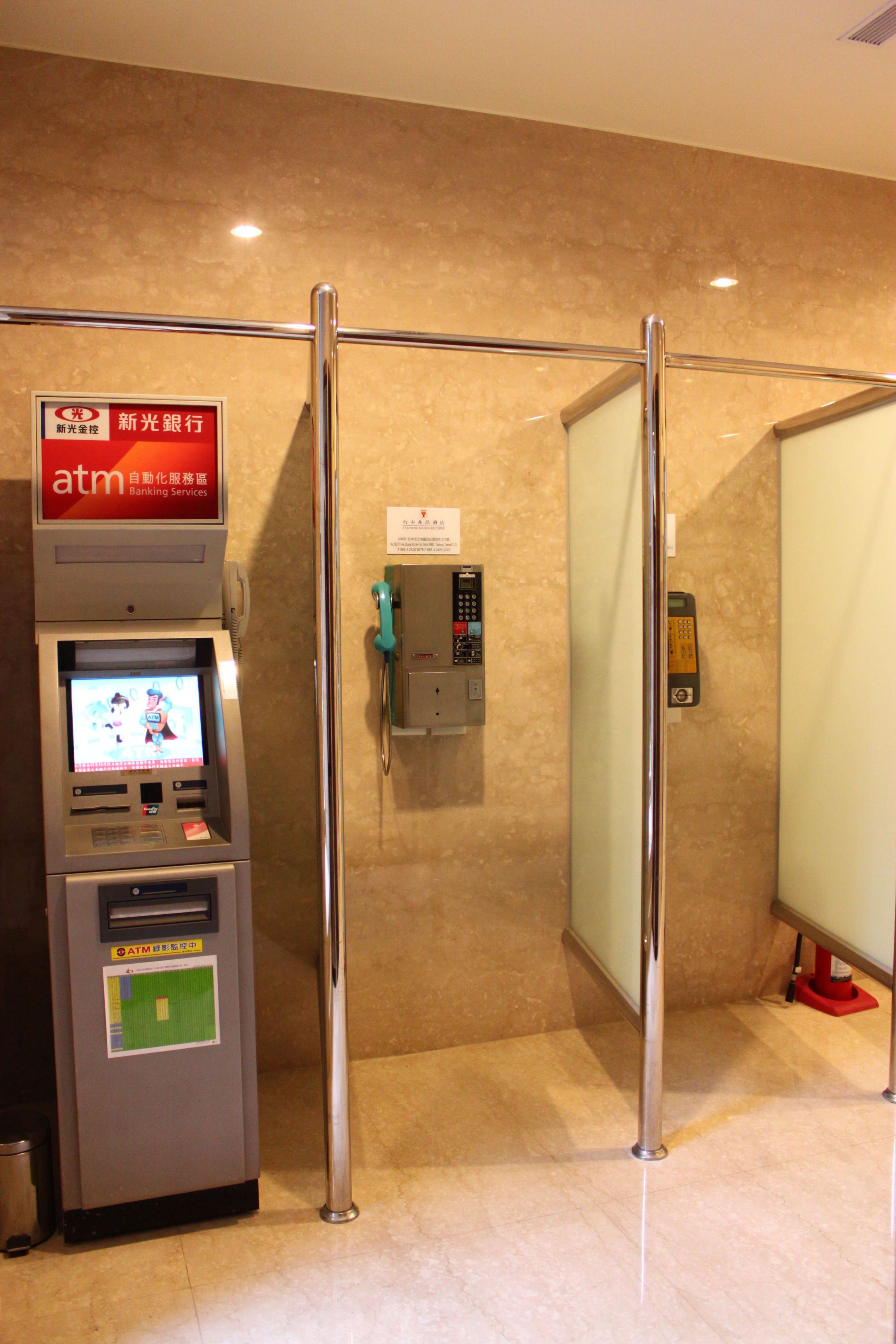 An ATM machine with a screen displaying a cartoon, a telephone, and a glass partition.