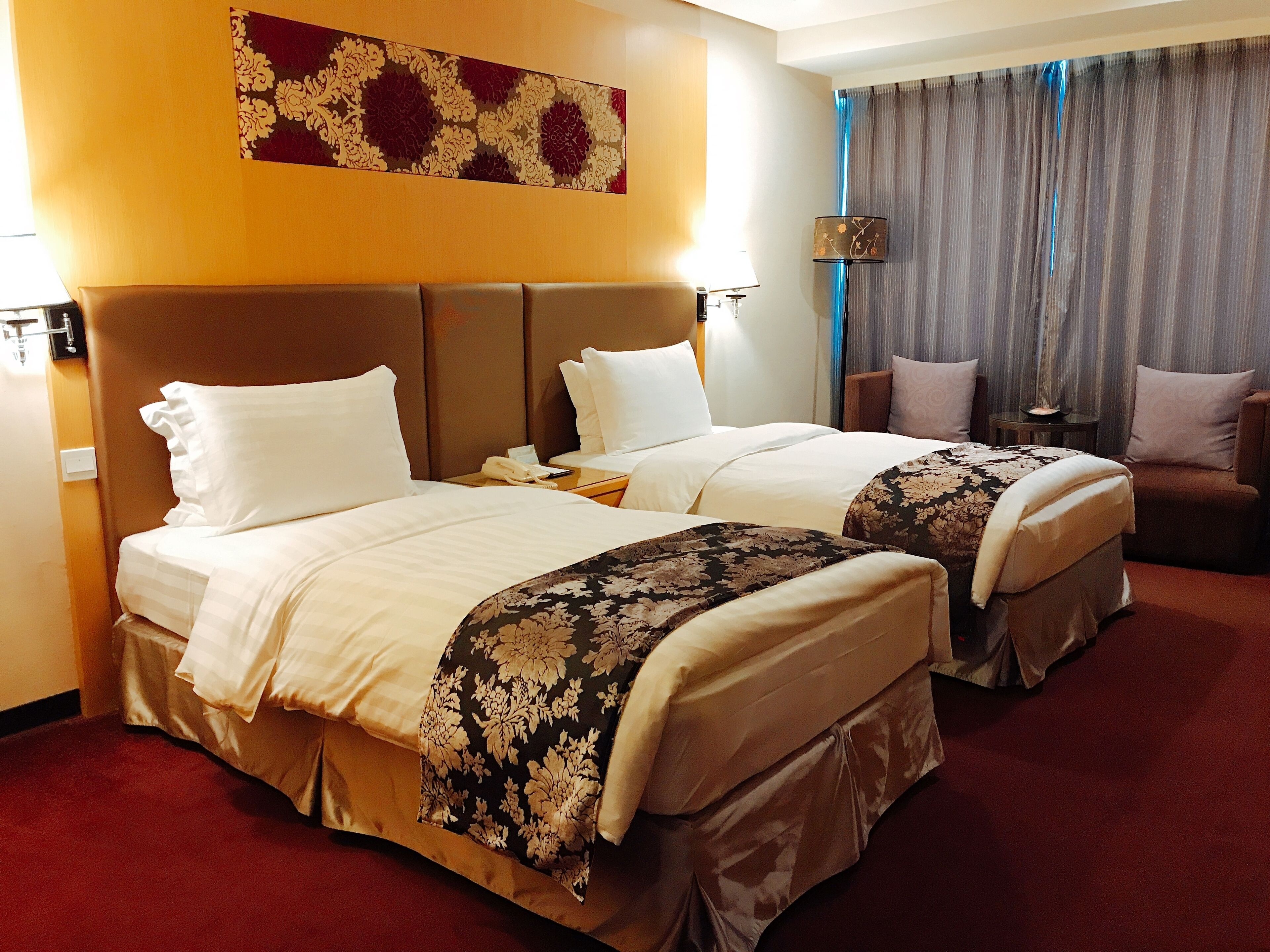 Habitación de hotel con dos camas, un sofá, una lámpara y un adorno en la pared.