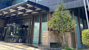 Un hotel moderno con fachada de vidrio, varios pisos y una entrada destacada con marquesina.