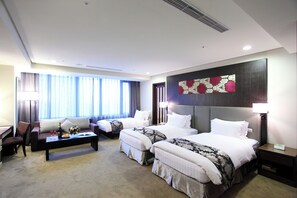 Habitación de hotel con dos camas, un sofá, una mesa de centro y un escritorio.