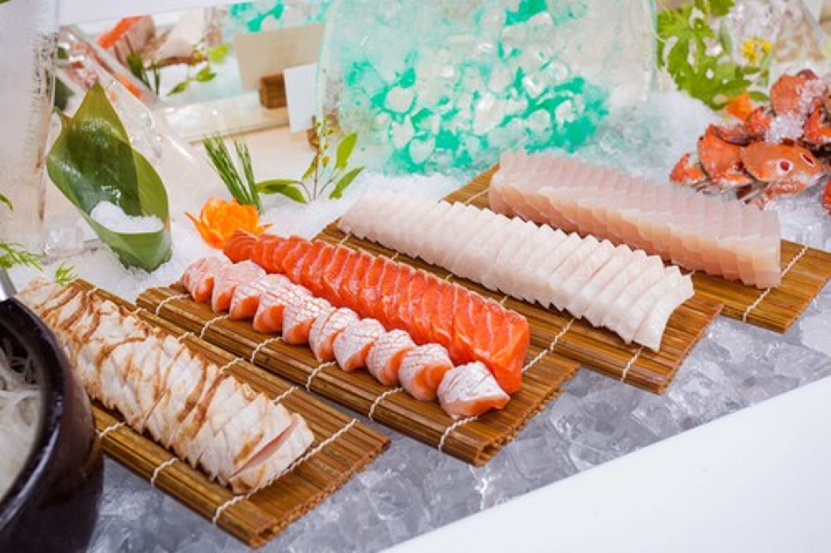 A variety of sushi on wooden trays with ice, surrounded by decorative elements.