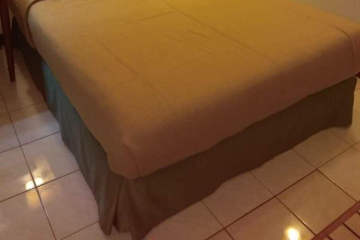 Un lit bien fait, avec une tête de lit en bois et deux lampes de chevet.
