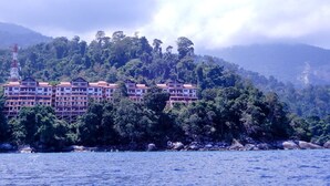 Un hotel frente al mar con múltiples balcones, rodeado de exuberante vegetación.