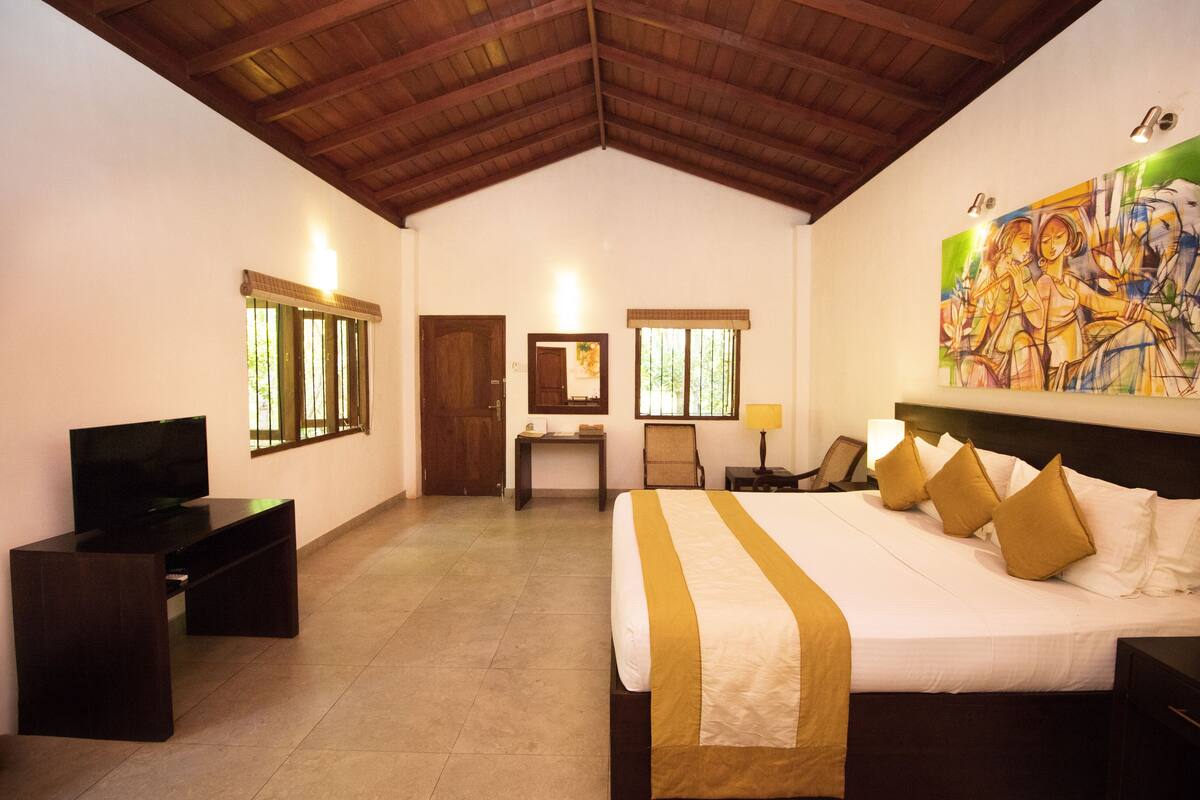 Habitación de hotel con una cama grande, un escritorio, un televisor y un cuadro en la pared.