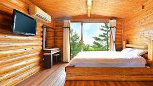 Ein Zimmer in einer Blockhütte mit einem Bett, einem Fernseher und einem Schreibtisch.