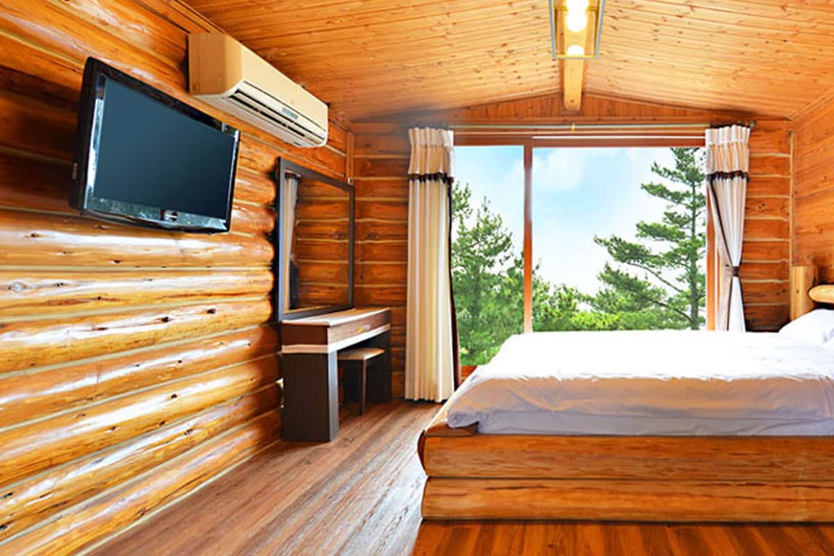 Una habitación tipo cabaña de madera con una cama, un televisor y un escritorio.