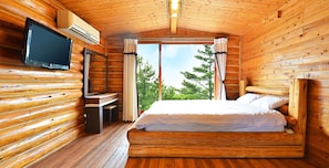 Una habitación tipo cabaña de madera con una cama, un televisor y un escritorio.