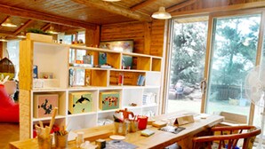Een gezellig houten interieur met wanden en plafonds, een groot raam en een eethoek met tafel en stoelen.