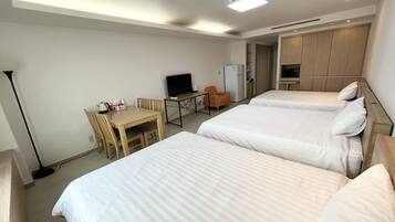 A hotel room with two beds, a desk with a chair, a television, and a wardrobe.