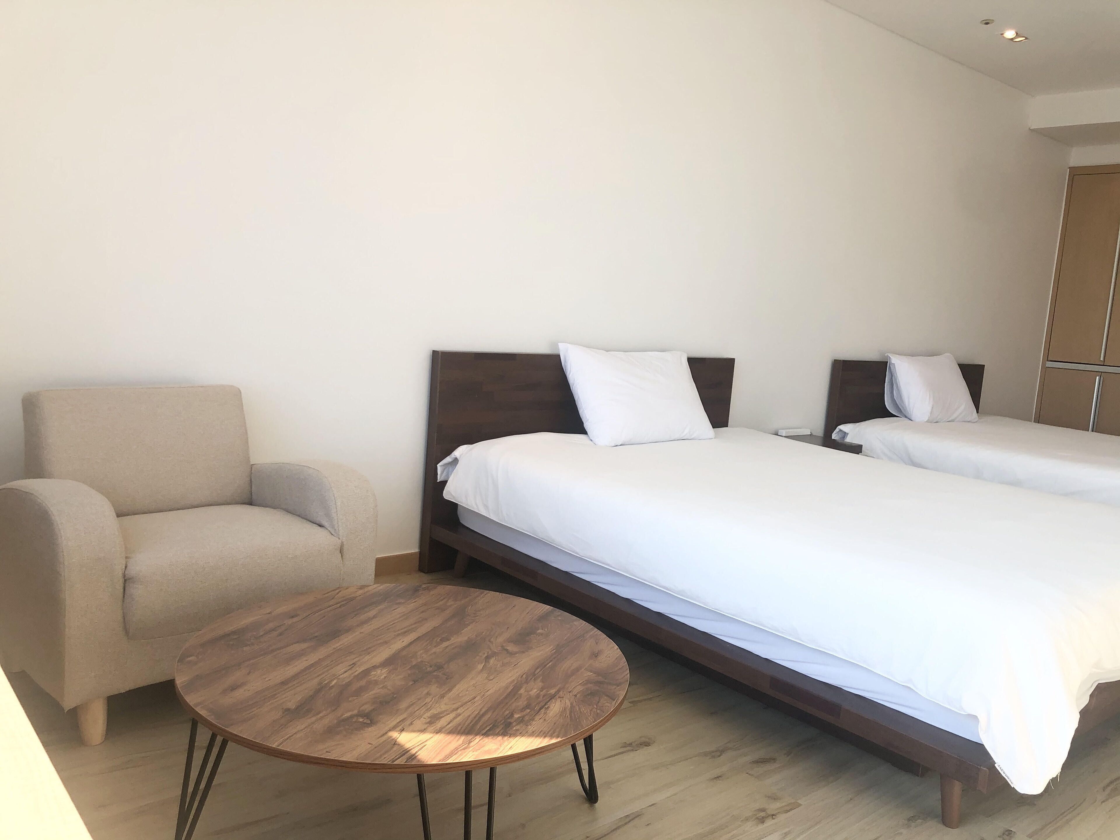 A hotel room with two single beds, a sofa, and a round wooden table.