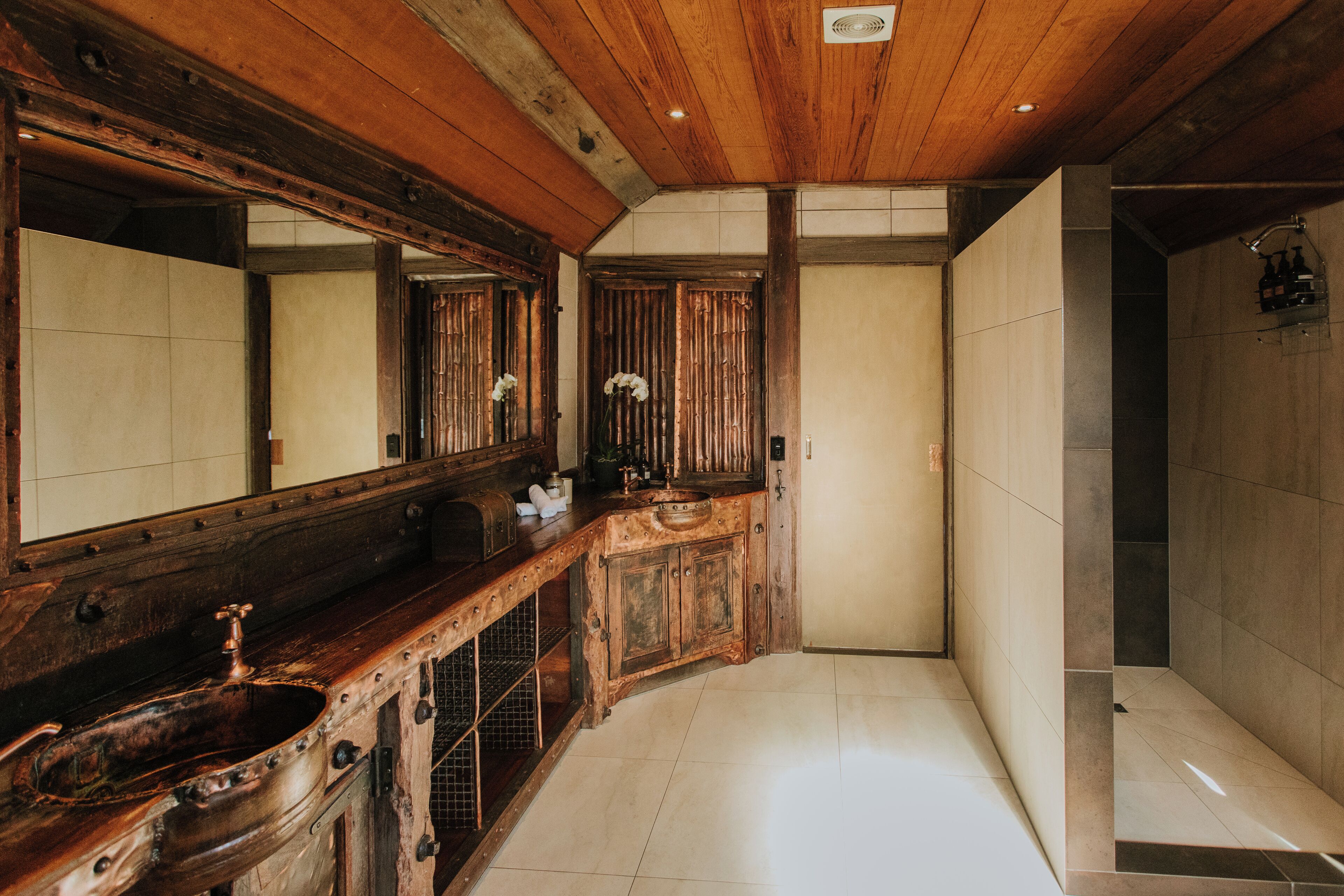 A bathroom with a wooden vanity, a large mirror, and a shower area.