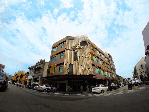 A multi-story hotel with a modern facade, featuring vertical wooden slats and a sign reading "Le Dream."