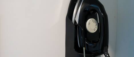 A wall-mounted iron with a control dial, a power cord, and a black and white patterned cloth.