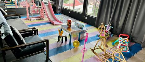 A children's play area with a slide, rocking horse, and various toys.