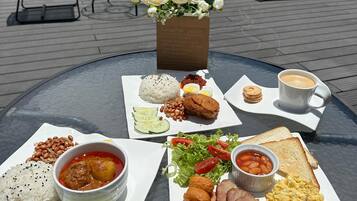 Une table avec divers aliments pour le petit-déjeuner, notamment du riz, des œufs, des haricots, du pain et une tasse de café.