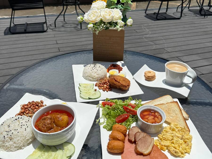 Ein Tisch mit verschiedenen Frühstücksangeboten, darunter Reis, Eier, Bohnen, Brot und einer Kaffeetasse.