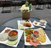 Une table avec divers aliments pour le petit-déjeuner, notamment du riz, des œufs, des haricots, du pain et une tasse de café.