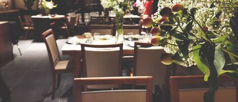 A restaurant with tables set for dining, chairs, and a floral centerpiece.