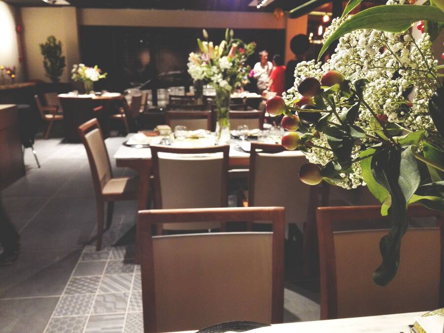 A restaurant with tables set for dining, chairs, and a floral centerpiece.