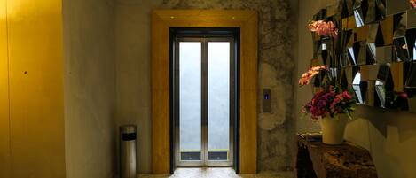 A hallway with a wooden door, a trash bin, and a wall-mounted mirror.