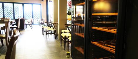 A restaurant interior with tables and chairs, a large window, and a black shelving unit.