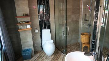 A modern bathroom with a glass shower enclosure, a white toilet, a sink with a mirror, and wooden shelves with toiletries.