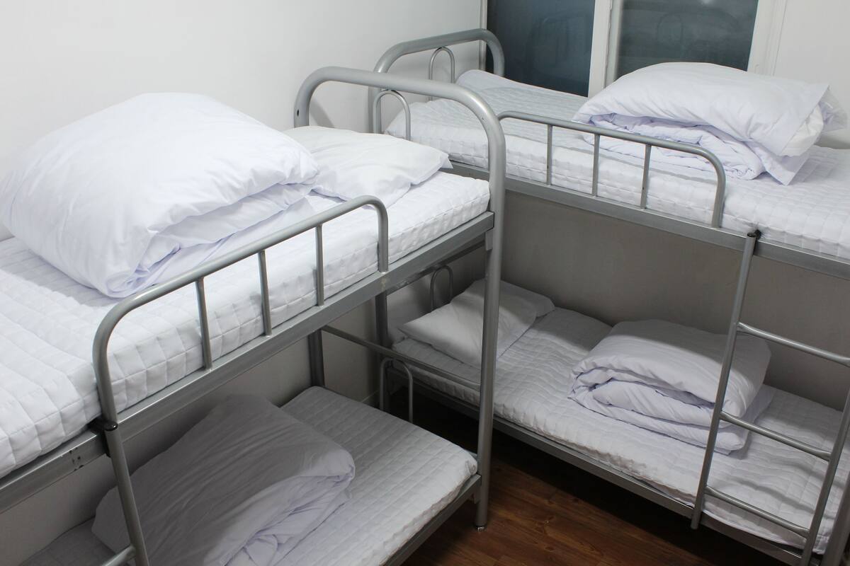 A bunk bed room with metal railings and white bedding.