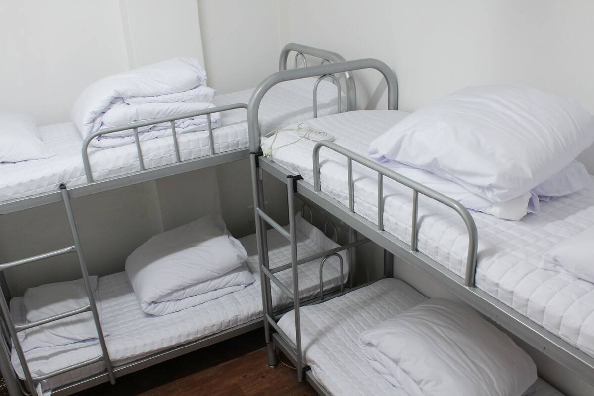 A bunk bed room with metal railings and white bedding.