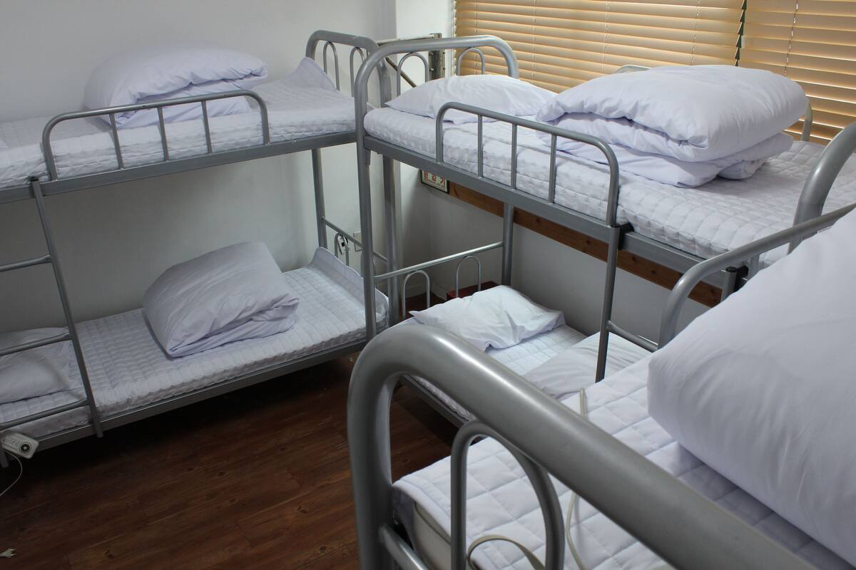 A bunk bed room with metal railings and white bedding.